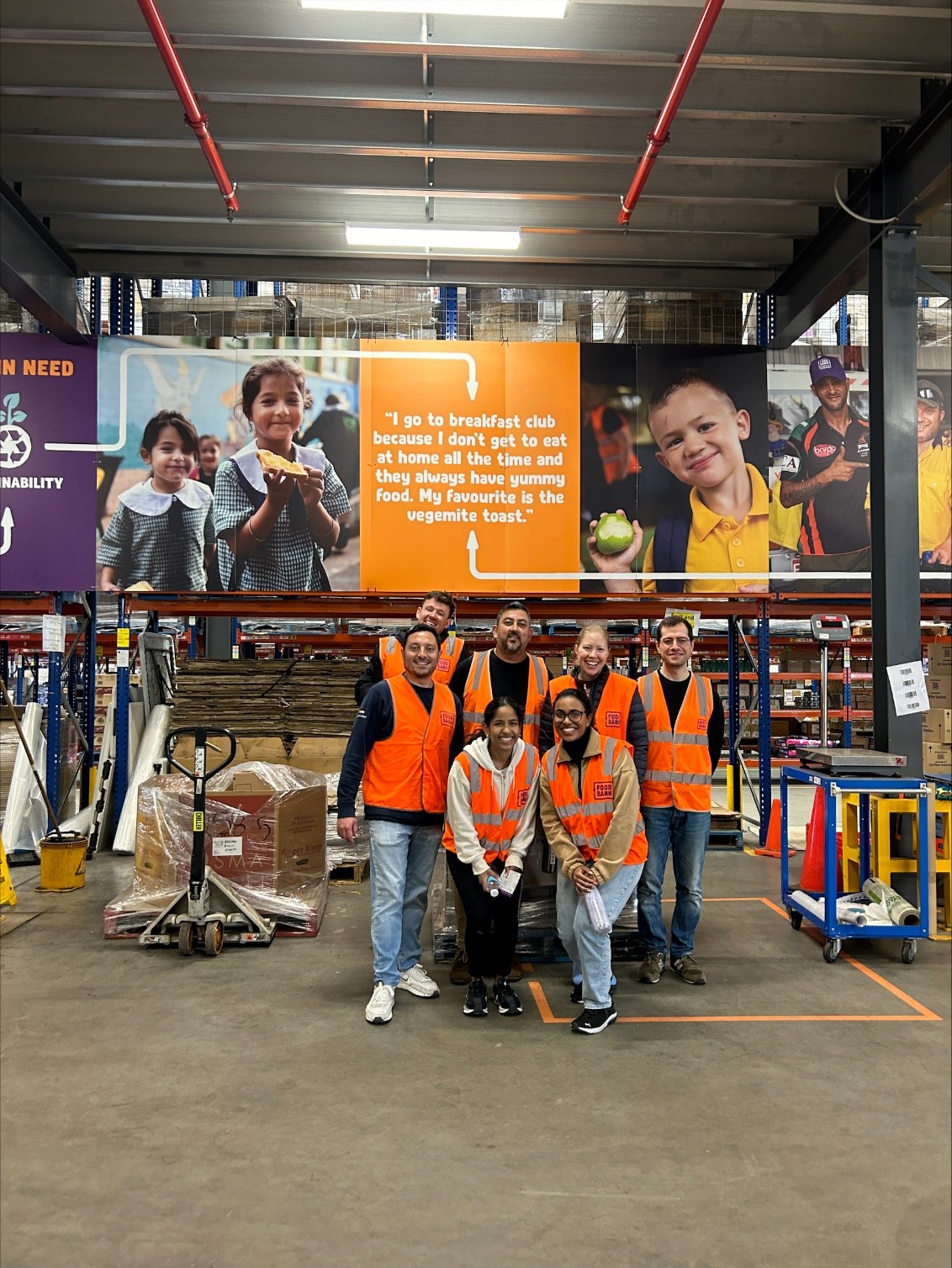 A group of people in orange vests in a warehouse

Description automatically generated