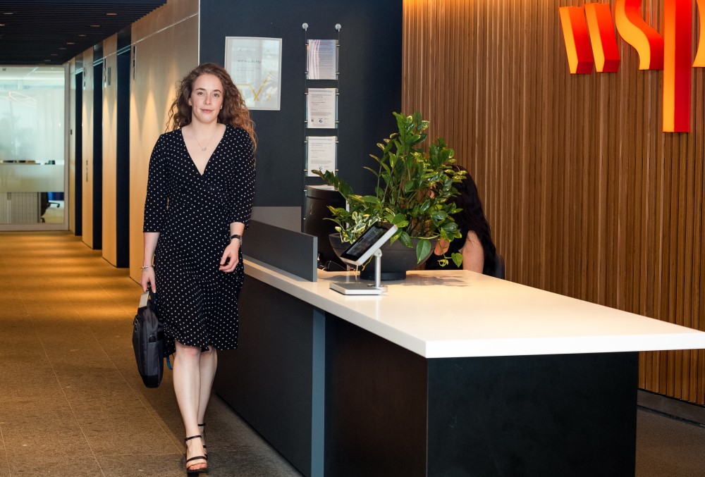 WSP Graduate- A young female professional passing by the company reception area.