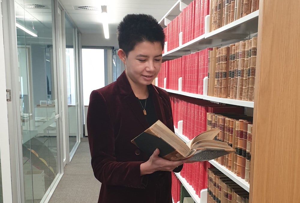 AGD Graduate - Young female lawyer reading a book at the library.