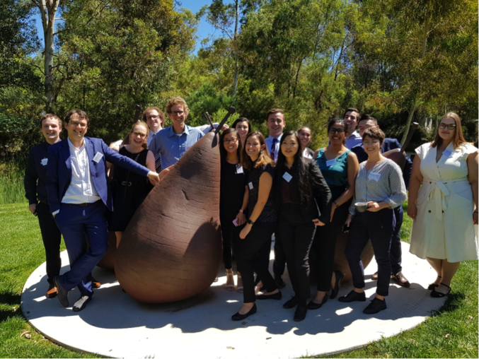 A group of graduates posing beside a pear shaped statue