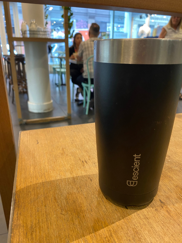 Escient Graduate- black tumbler inside the coffee shop