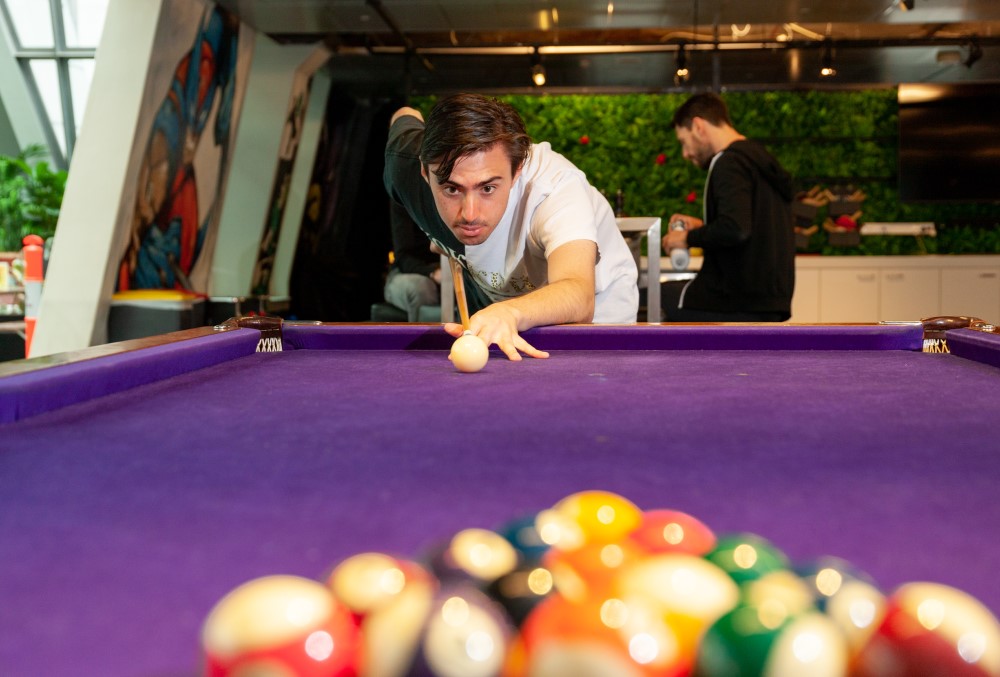 Optiver Graduate- Young professional male playing pool after work.