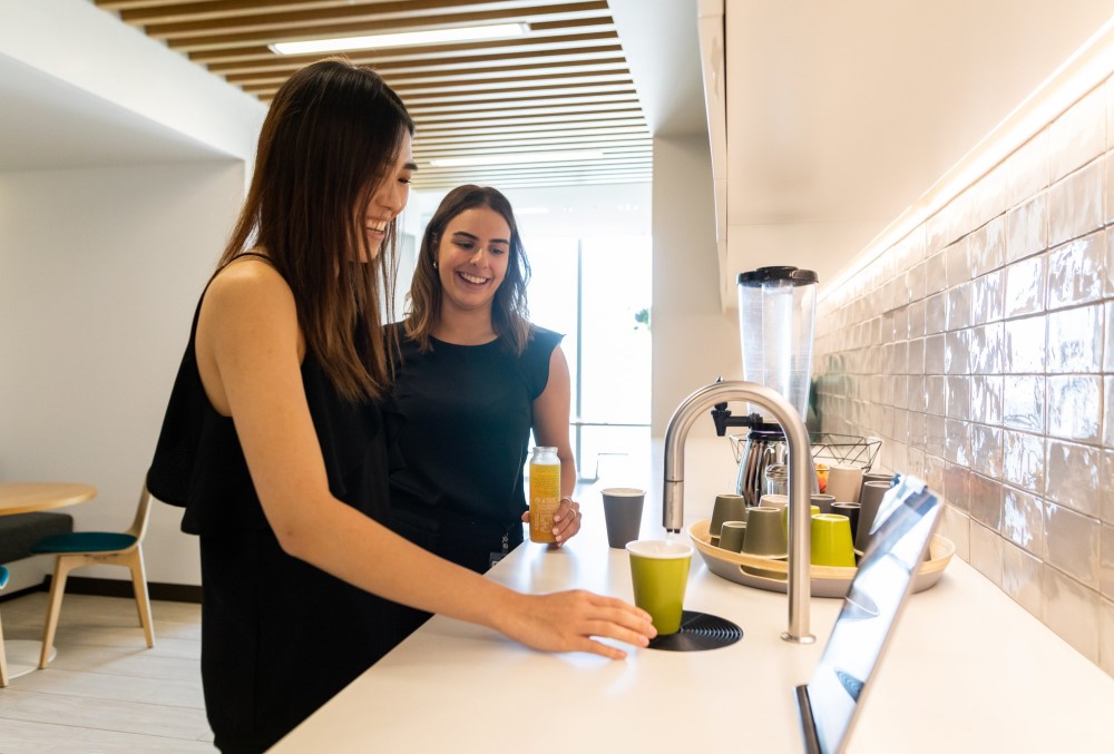 Deloitte Graduate- Two young female professionals getting water at the kitchen.