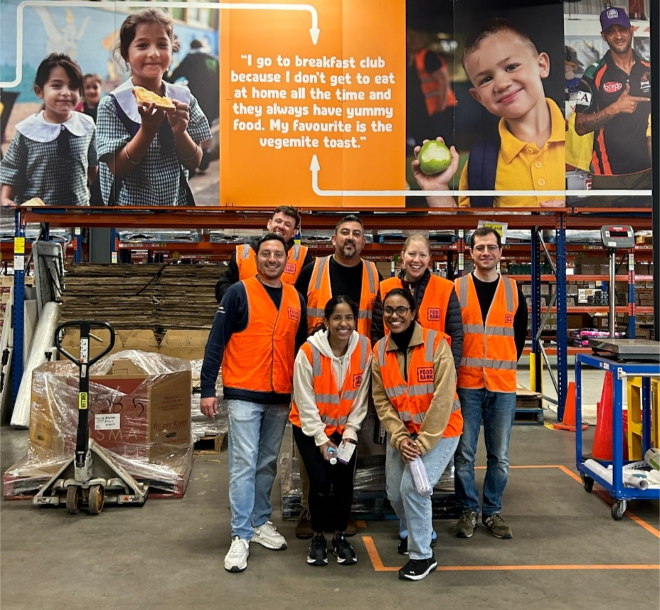 A group of people in orange vests in a warehouse

Description automatically generated