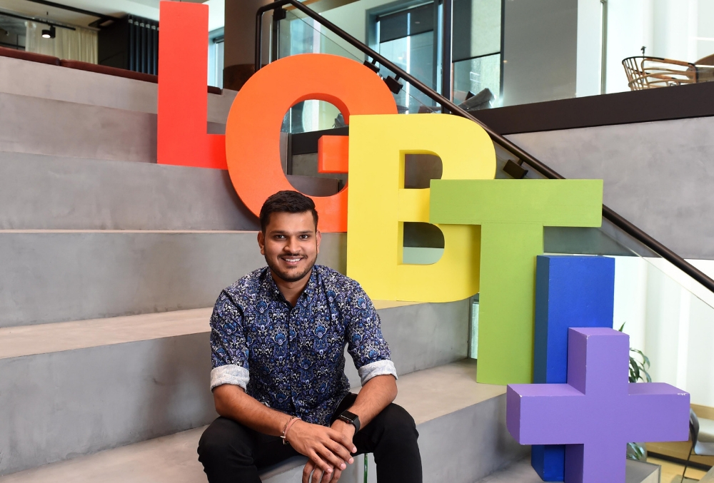Rana infront of the LBGT logo in the office