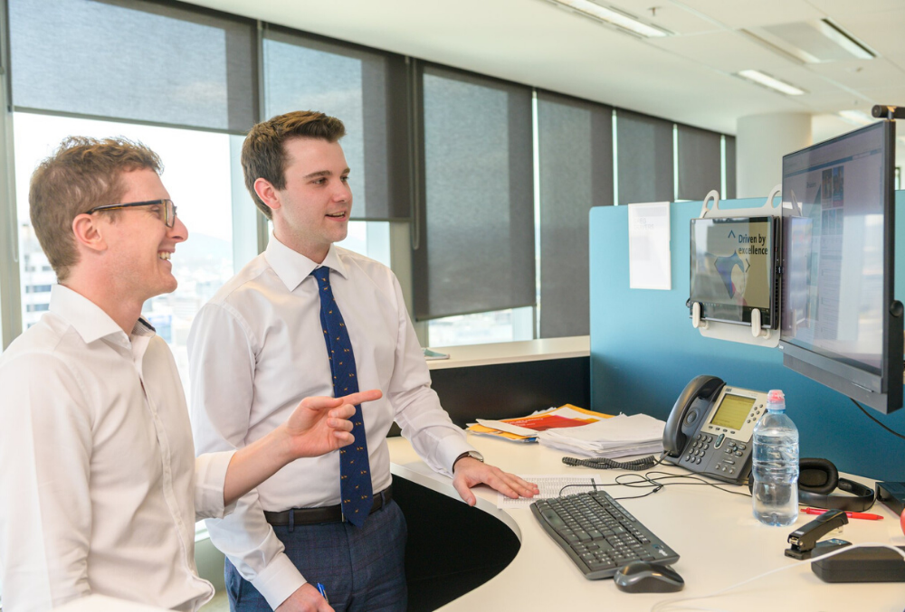 Conor having a discussion with associate at his desk