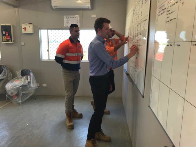 A young professional writing up on the site whiteboard with his colleagues