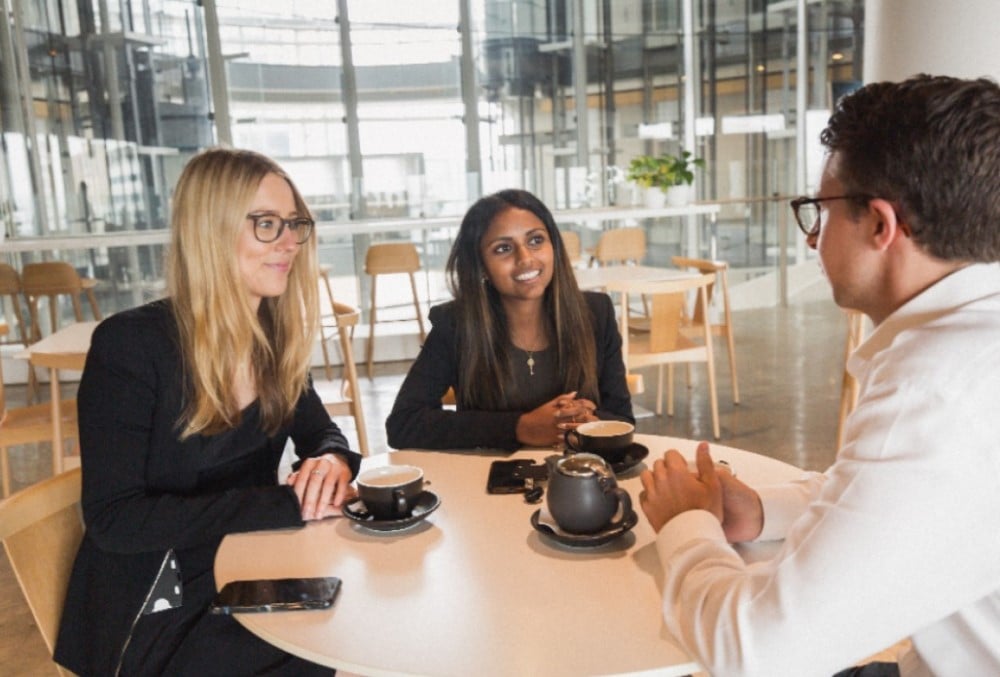 Clayton Utz - Young female lawyer having coffee with her team.