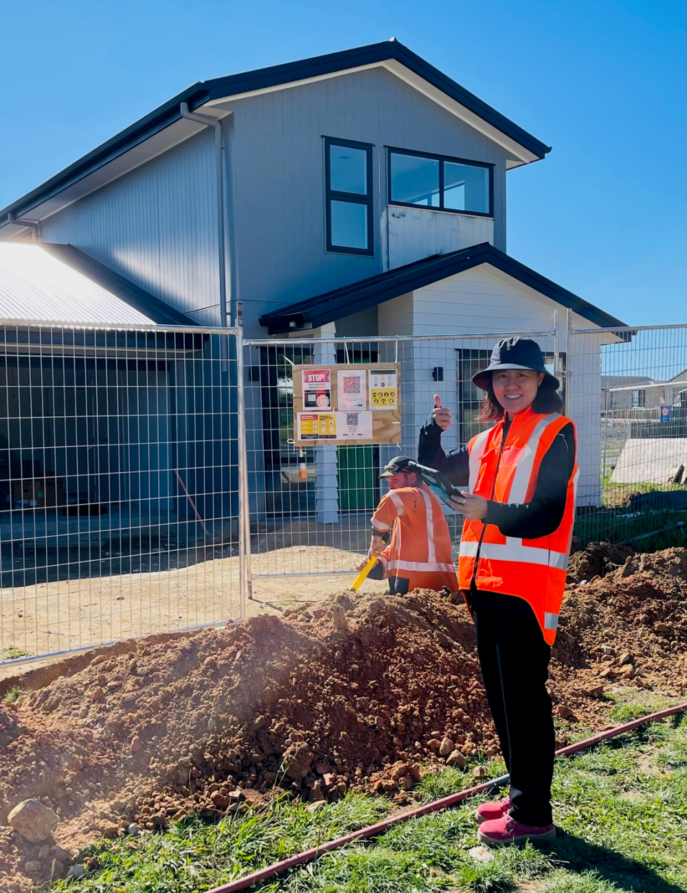 Hamilton City Council Graduate - Young professional standing on a site with a house on the background.